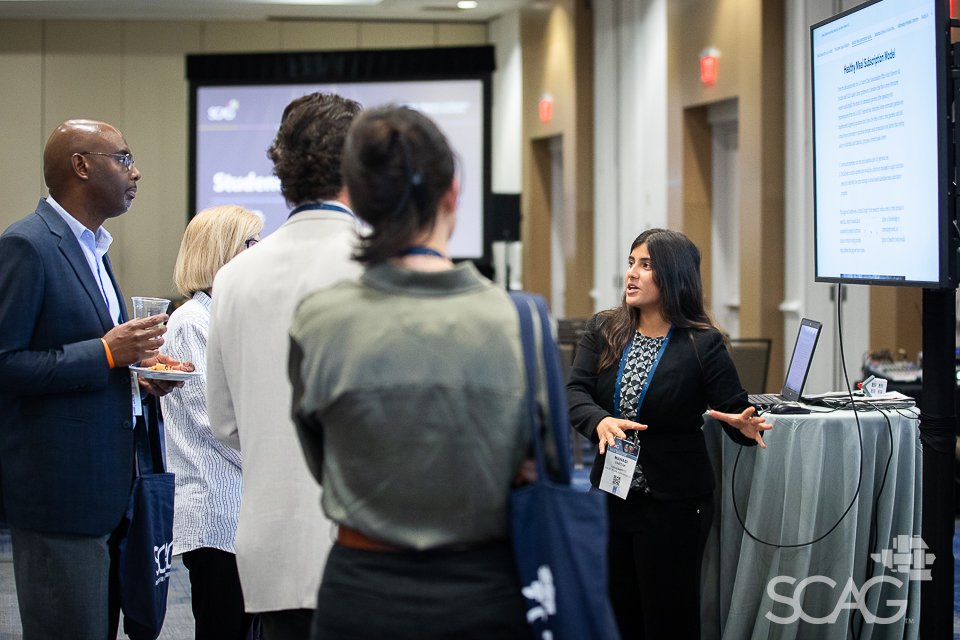 Group listening to presentation near large screen in conference setting.