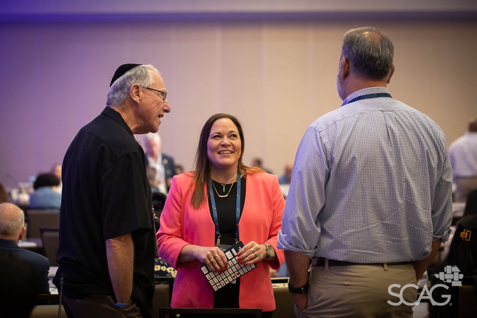 Three people talking and smiling in a conference room.