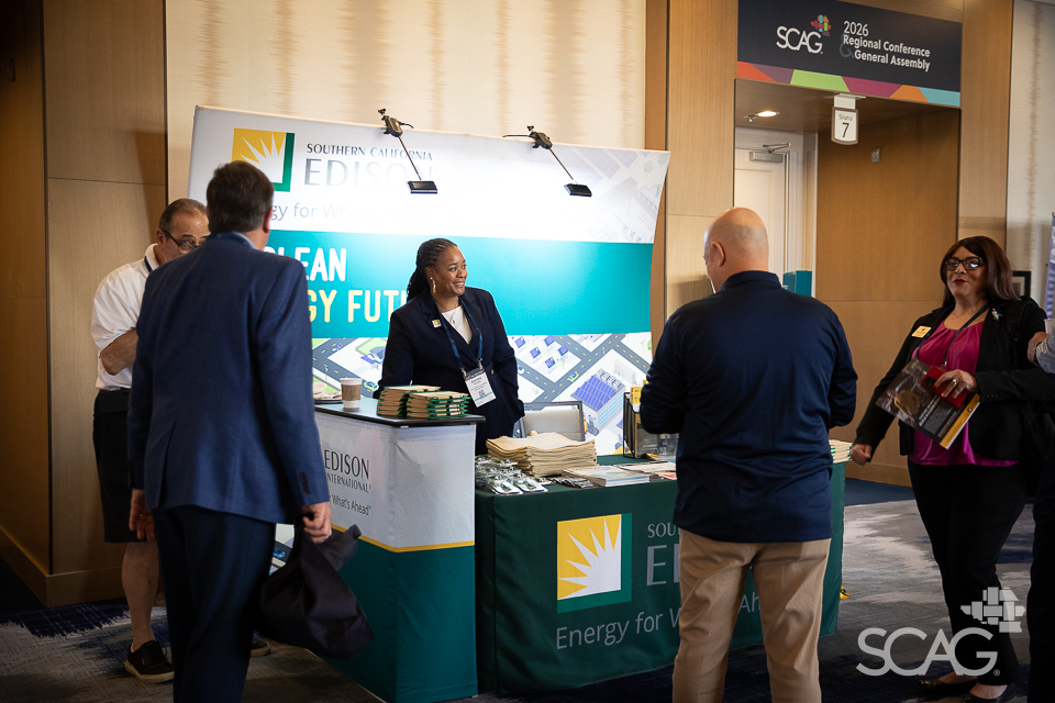 Trade show booth with people interacting, branded "Edison," bright lighting.