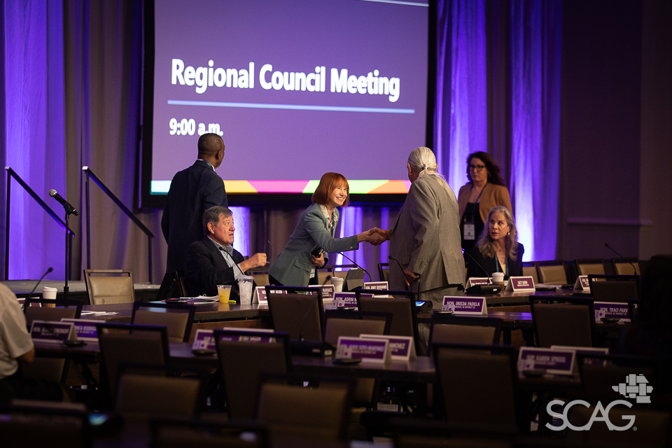 People conversing at a meeting in a purple-lit conference room.