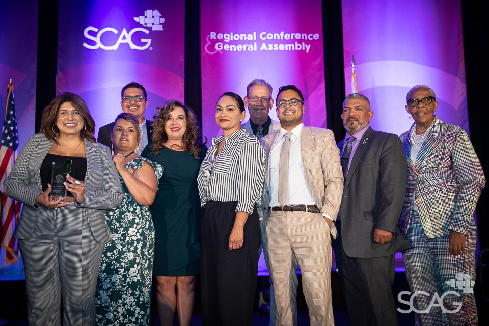 Diverse group posing at conference with purple backdrop.