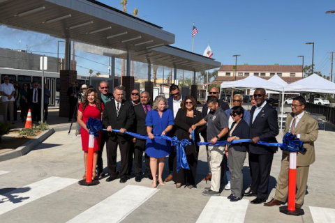Group of people at ribbon-cutting ceremony outdoors.