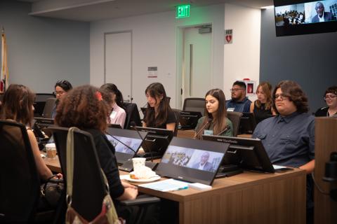 People seated in a conference room, engaging in a meeting.