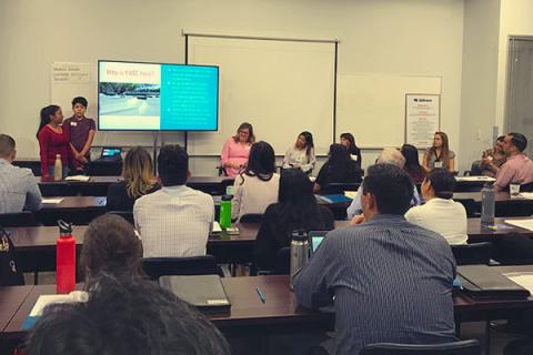 Classroom presentation with attendees seated at tables.